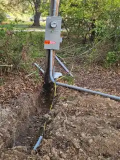 A meter pole with conduit running down into an open trench