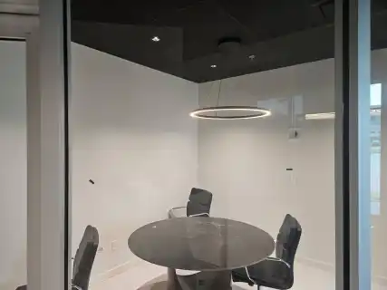 A glass-walled conference room with a round ring light over a table