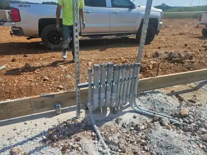 Conduit stub-ups on strut beside the forms, with a work truck behind
