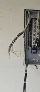 A new panel mounted on a bare wall with cables run in, ready to terminate