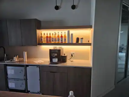 A break room with dark cabinets and a lit shelf above the counter