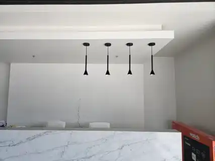 Four black pendant lights over a white quartz island