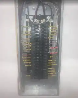 A panel in a wall with yellow-tagged wires landed on the breakers