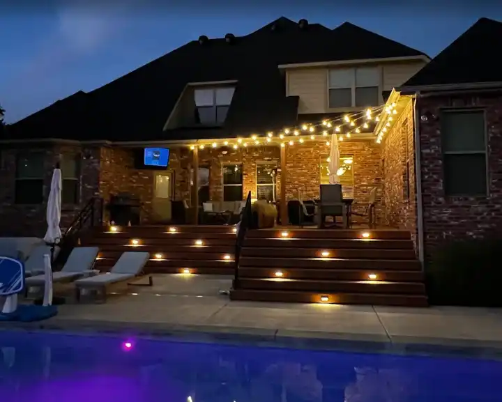 A pool deck at dusk with step lights and string lights